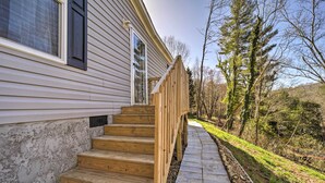 A wooden deck leading to a house with a stone pathway and a natural landscape. - Asheville Area Home Near Blue Ridge Mountains (Leicester)