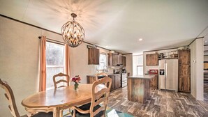 A modern kitchen with wooden cabinets, a central island, and a dining area with a wooden table and chairs. - Asheville Area Home Near Blue Ridge Mountains (Leicester)