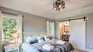 Une chambre à coucher avec un lit, une table de chevet, une lampe et une vue sur l’extérieur par une fenêtre.