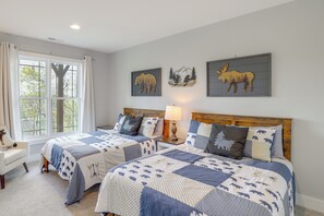 Un dormitorio con dos camas, una ventana con cortinas, una lámpara y cuadros en la pared.