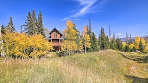 A lodge with a prominent front porch, surrounded by tall trees and a grassy hill. - Ski-in/ski-out Cabin: Lift to Brian Head Resort! (Brian Head)