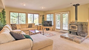 A living room with a sectional sofa, a television, a fireplace, and large windows. - Ski-in/ski-out Cabin: Lift to Brian Head Resort! (Brian Head)