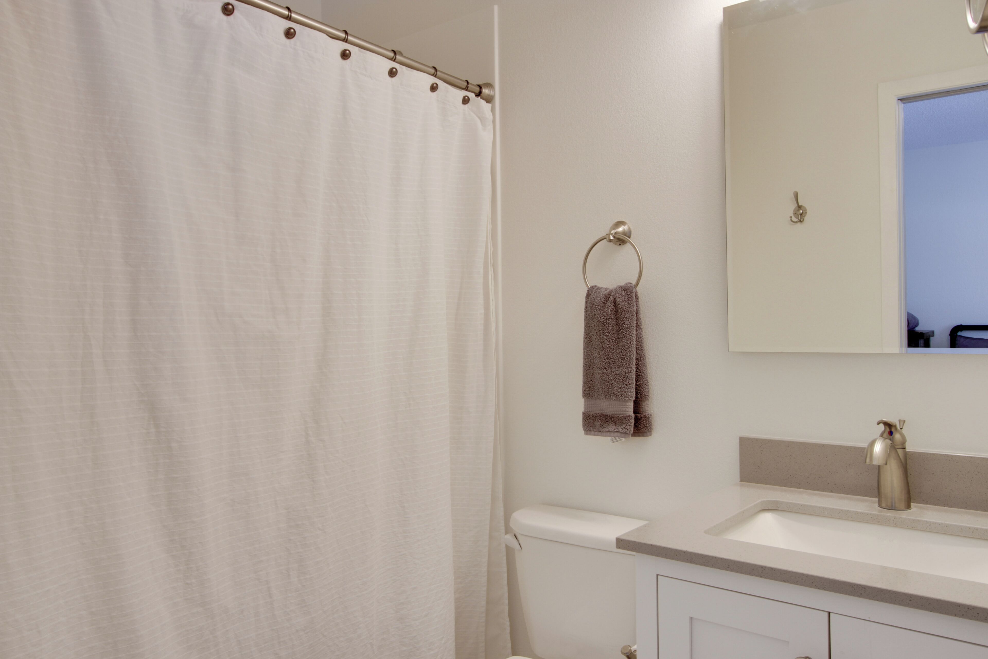 A bathroom with a shower curtain, a towel ring with a towel, a sink, and a mirror.