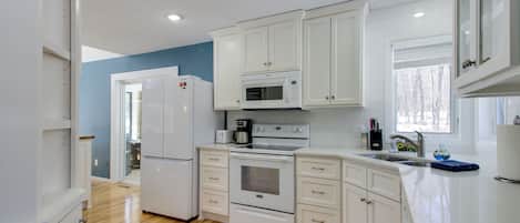 A modern kitchen with white cabinets, a microwave, an oven, and a refrigerator.
