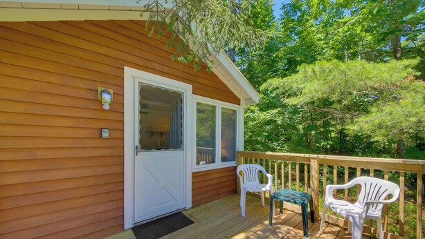 A wooden deck with two white plastic chairs and a small table, a white door, and a window. - Couples Getaway Near Beaches: Northport Cottage (Lincolnville)