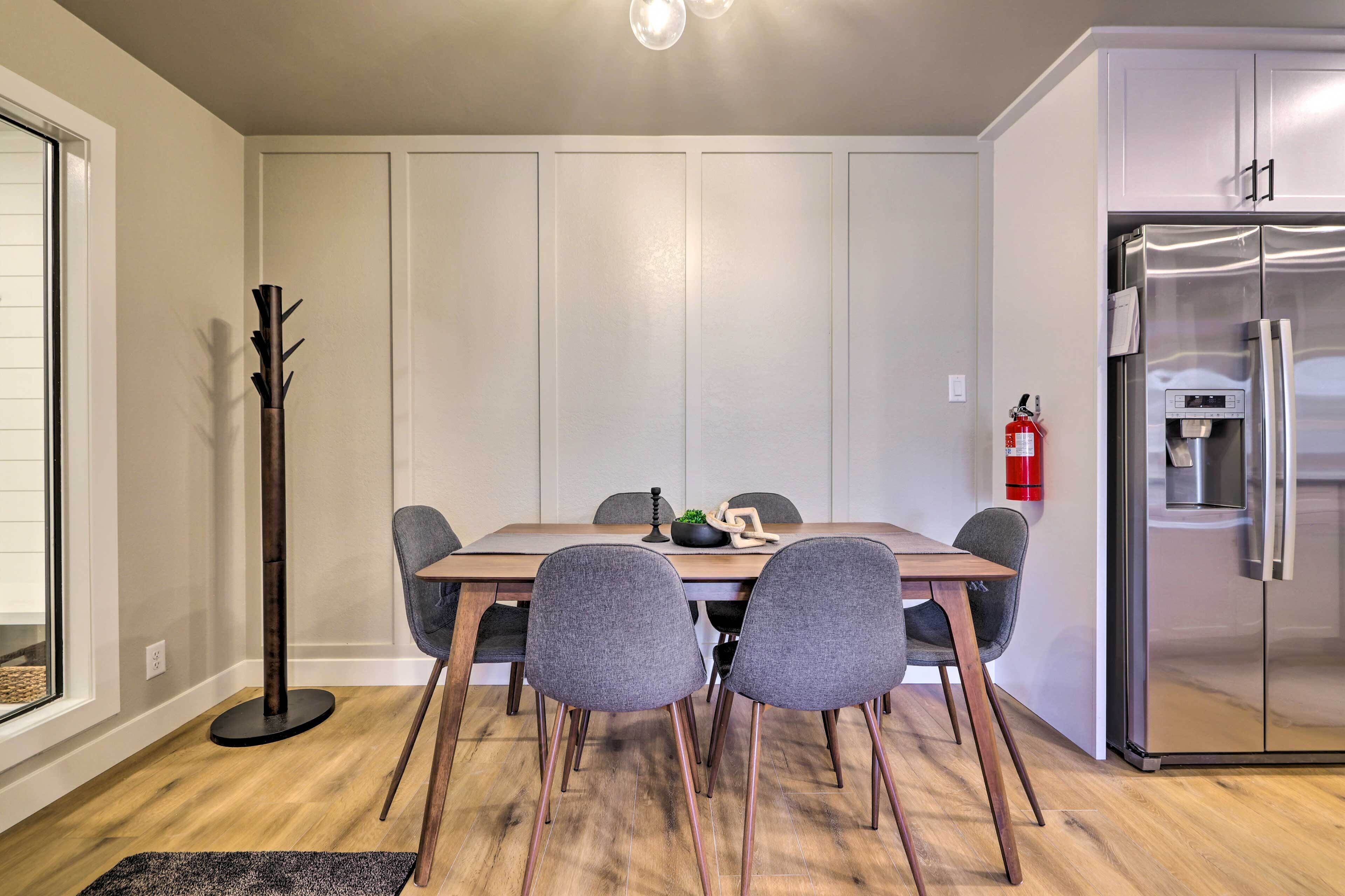Et moderne køkken med et rustfrit stål køleskab, et spisebord med fire stole, og en høj gulvlampe.