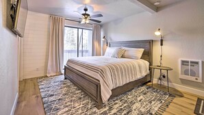 A bedroom with a bed, a ceiling fan, a window with curtains, a bedside table with a lamp, and an air conditioning unit. - Brian Head Condo Near Lifts at Giant Steps! (Brian Head)