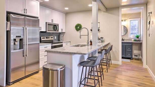 A modern kitchen with stainless steel appliances, a granite countertop, and a bar area with stools. - Brian Head Condo Near Lifts at Giant Steps! (Brian Head)