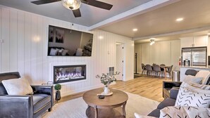 A modern living room with a fireplace, a ceiling fan, and a dining area with a kitchen in the background. - Brian Head Condo Near Lifts at Giant Steps! (Brian Head)
