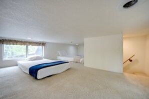 A bedroom with a large bed, a smaller bed, a window with curtains, and a ceiling vent. - Fredericksburg Cabin Rental on a 27-acre Winery! (Fredericksburg)