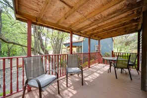 Un espace extérieur abrité, doté de chaises et d’une table, entouré d’une terrasse en bois et de rampes rouges.