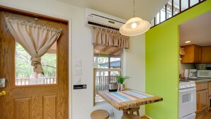Una cocina con una mesa de madera, taburetes, estufa y microondas.