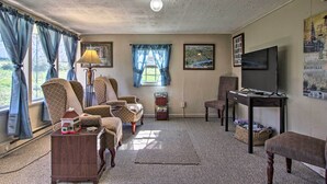A cozy living room with patterned armchairs, a television, and a small table with a lamp. - 2 Mi to Downtown Knoxville: Cozy Home w/ Patio (Knoxville)