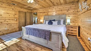 Een slaapkamer met houten lambrisering, een bed, nachtkastjes en een plafondventilator.