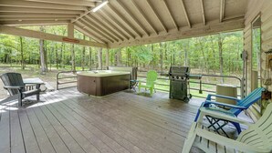 Een overdekt terras buiten met een jacuzzi, barbecue en zithoek.