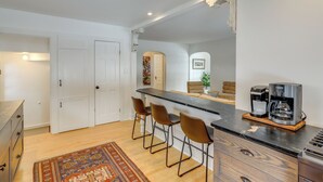 A modern kitchen with a bar area, wooden cabinets, and a coffee machine. - Cozy Cottage in Historic Village: Near Cedar Point (Milan)