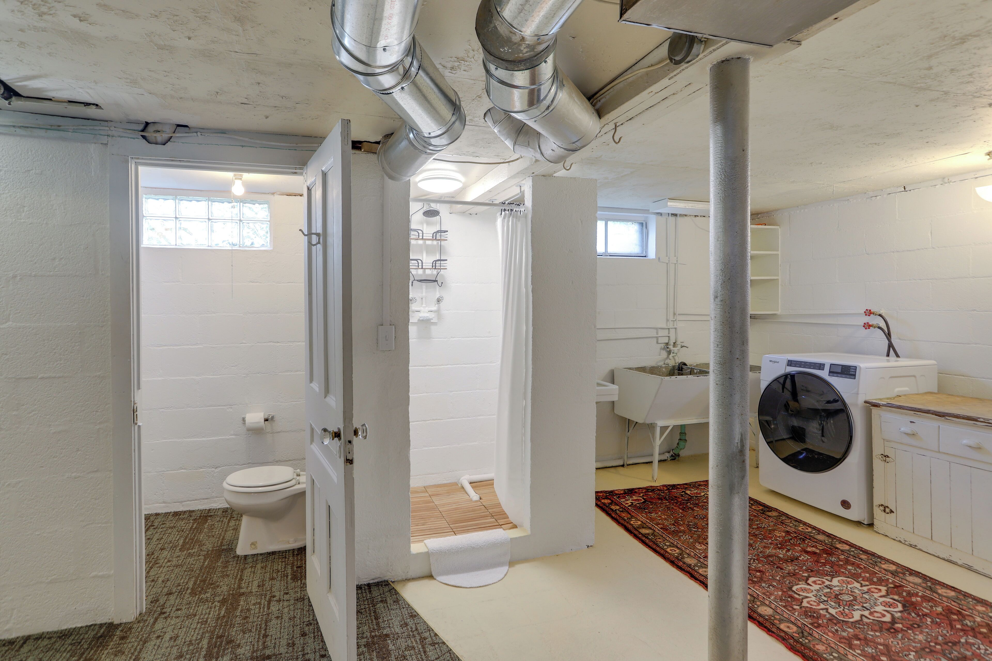 Een compacte, moderne badkamer met toilet, douche en wasmachine.