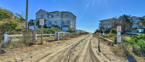 A coastal road leading to a multi-story building with a 'No Parking - Any Time' sign.