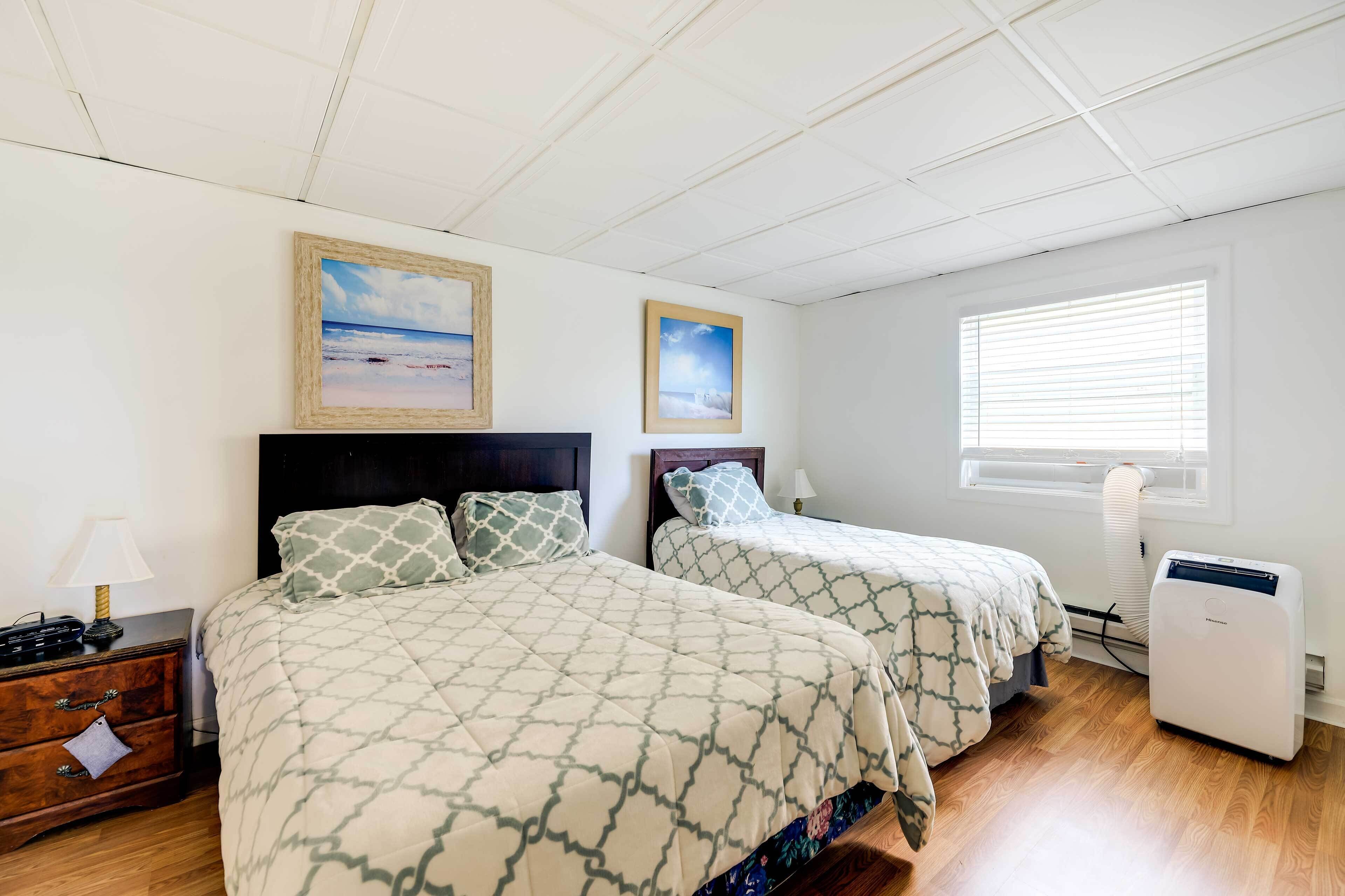 A bedroom with two beds, a nightstand, a heater, and a window with blinds.