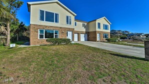 A two-story residential building with a brick facade, large windows, and a well-maintained lawn. - 'hannah's Place' - Quaint & Cozy Apt by the Beach! (Emerald Isle)