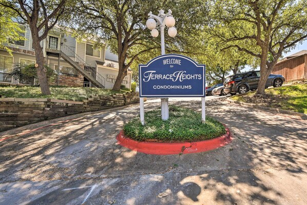A welcome sign for Terrace Heights Condominiums with a landscaped area and a staircase leading to a building.