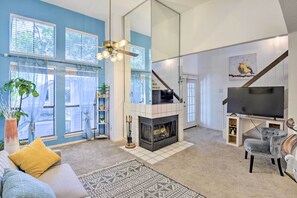 A living room with a fireplace, a sofa, a TV, and a staircase.