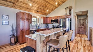 A spacious kitchen with wooden cabinets, a large island with bar stools, stainless steel appliances, and a wooden ceiling. - Fairplay Cabin w/ Wraparound Deck & Mountain Views (Fairplay)