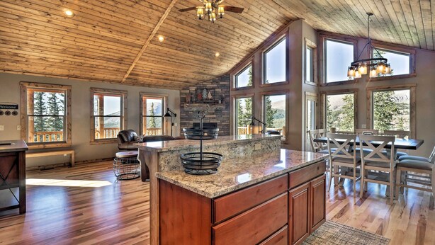 A spacious kitchen with a large island, wooden ceiling, and large windows offering views of the outdoors. - Fairplay Cabin w/ Wraparound Deck & Mountain Views (Fairplay)