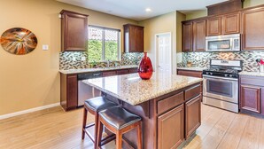 A kitchen with wooden cabinets, a granite countertop, a red vase, and a stainless steel oven.