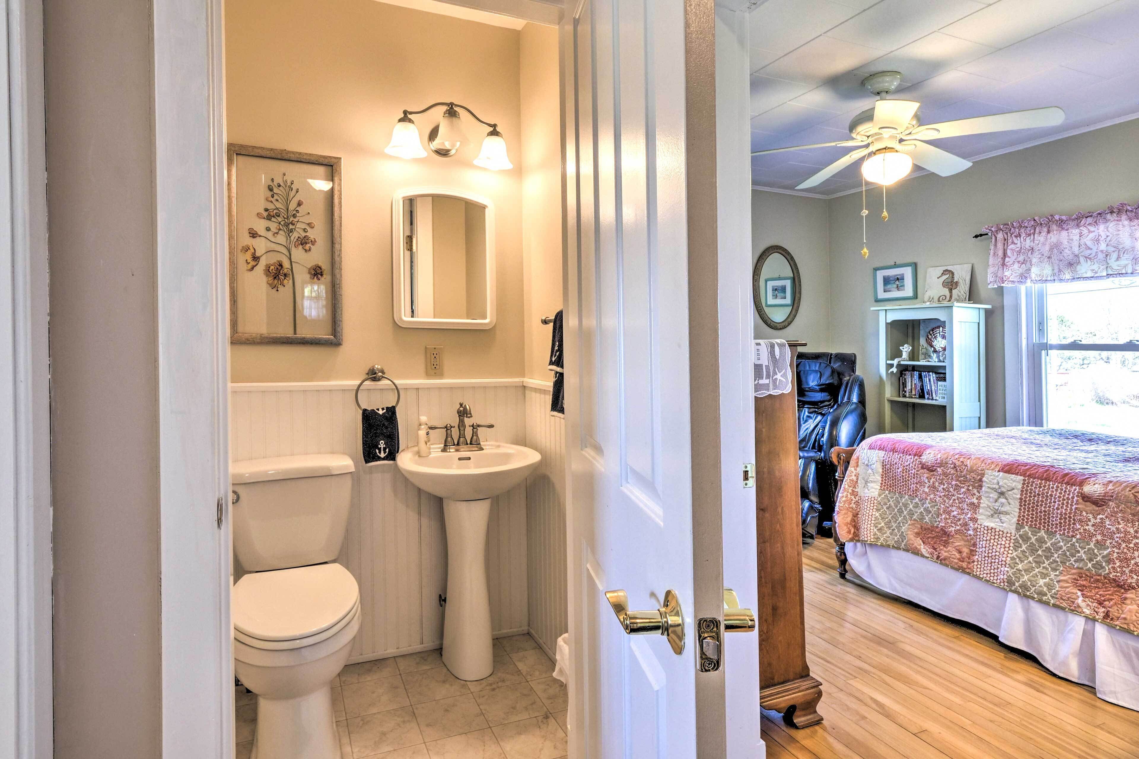 A bathroom with a toilet, sink, and mirror.