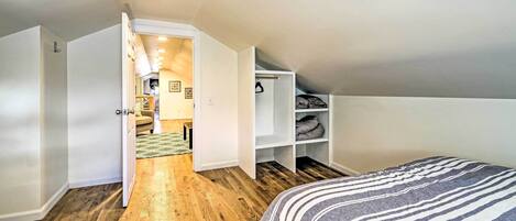 Ein Schlafzimmer mit zwei Betten, Holzboden und einem Kleiderschrank mit Regalen.