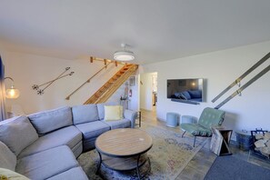 A modern living room with a sectional sofa, a round coffee table, and a TV mounted on the wall. - Updated Rustic Retreat Cabin: Walk to Payette Lake (McCall)