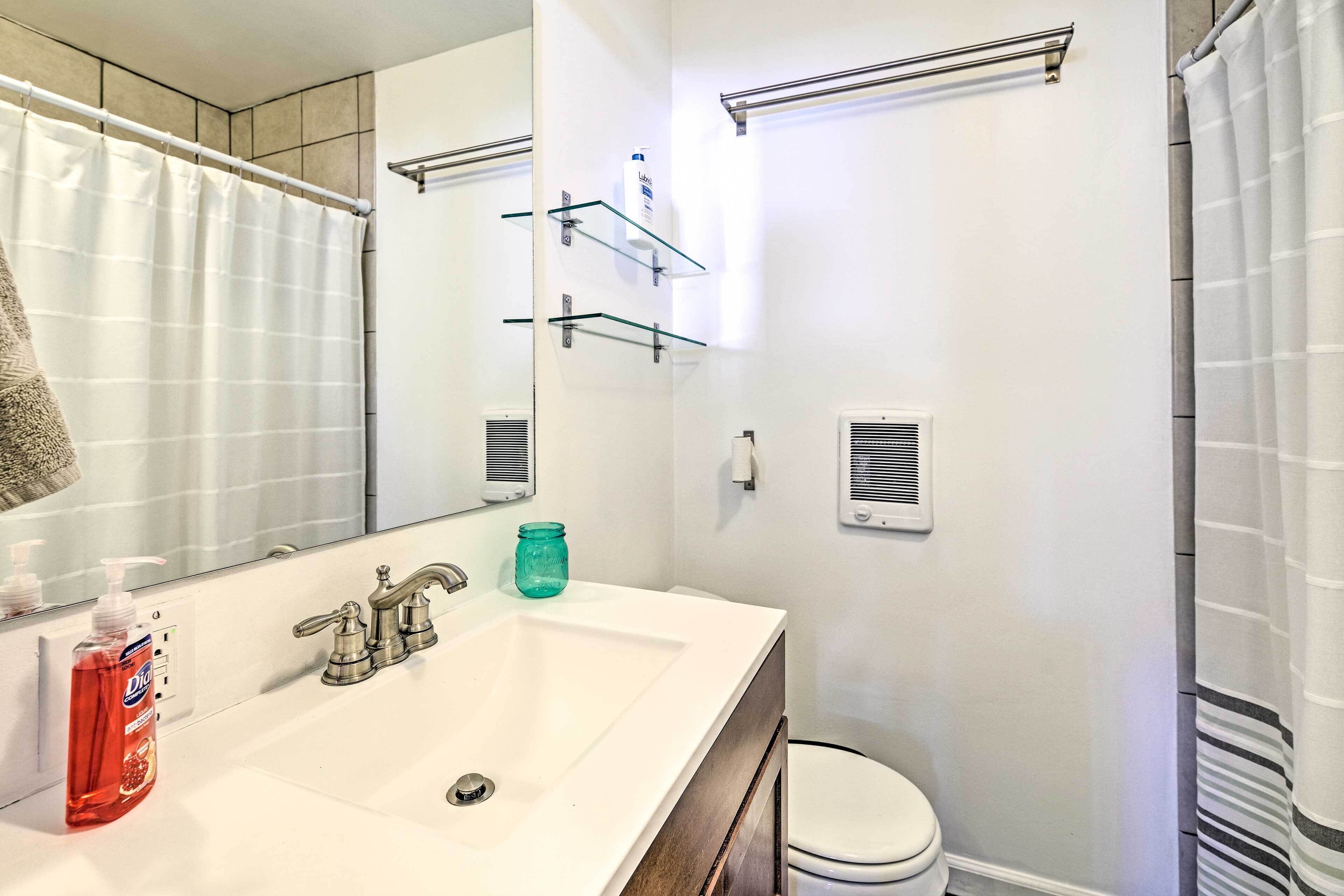 A bathroom with a white sink, a mirror, a toilet, and a shower curtain.