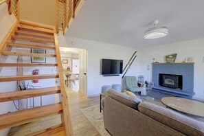 Ein modernes Wohnzimmer mit einer Holztreppe, einem Kamin, einem Fernseher und einem Sofa.