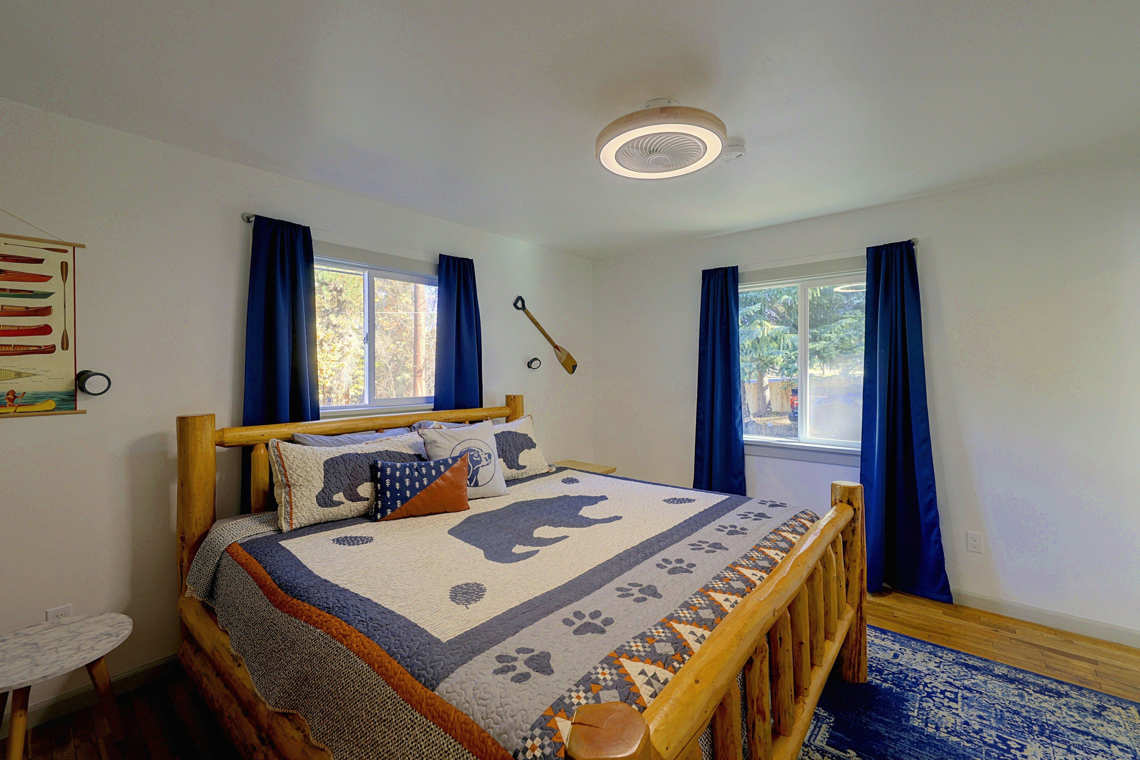 A bedroom with a bed, a window, a ceiling fan, and a wall-mounted clock.