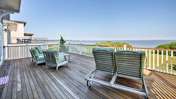 A wooden deck with outdoor furniture, a railing, and a view of the water. - Luxe Waterfront East Quogue Home w/ Beach On-site! (East Quogue)