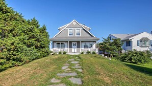 A two-story house with a front porch, a stone pathway leading to the entrance, and a well-maintained lawn. - Luxe Waterfront East Quogue Home w/ Beach On-site! (East Quogue)