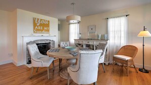 A dining area with a fireplace, a chandelier, and a dining table with chairs. - Luxe Waterfront East Quogue Home w/ Beach On-site! (East Quogue)