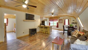 A spacious loft with a high ceiling, wooden floors, a central kitchen area with bar stools, a dining table, and a cozy seating area with a couch. - Pet-friendly Prospect Apartment: 7 Mi to Beach! (Stockton Springs)