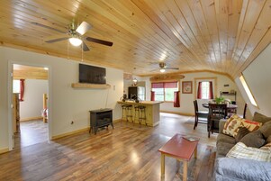 Un loft espacioso con techo alto, pisos de madera, una cocina central con taburetes de bar, una mesa de comedor y una zona de estar acogedora con un sofá.