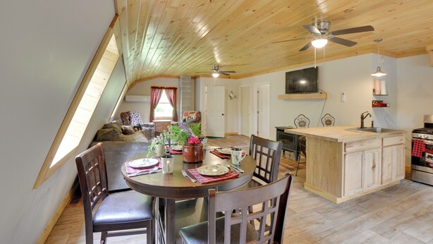 A dining area with a wooden ceiling, a kitchen island, and a dining table set for four. - Pet-friendly Prospect Apartment: 7 Mi to Beach! (Stockton Springs)