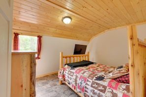 A bedroom with a wooden ceiling, a bed with a quilt, a window with curtains, and a small desk with a laptop. - Pet-friendly Prospect Apartment: 7 Mi to Beach! (Stockton Springs)