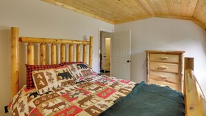 A bedroom with a wooden headboard, a quilted bedspread, a wooden dresser, and a door leading to another room. - Pet-friendly Prospect Apartment: 7 Mi to Beach! (Stockton Springs)