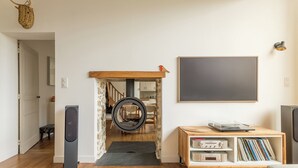 Un salon moderne avec un plancher en bois, un tableau noir, une bibliothèque contenant des disques vinyles et un mur en pierre.