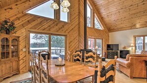 A wooden interior with a dining table, chairs, a sofa, and a television.