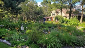 A well-maintained garden with a variety of plants and flowers, a birdhouse, and a small gazebo.