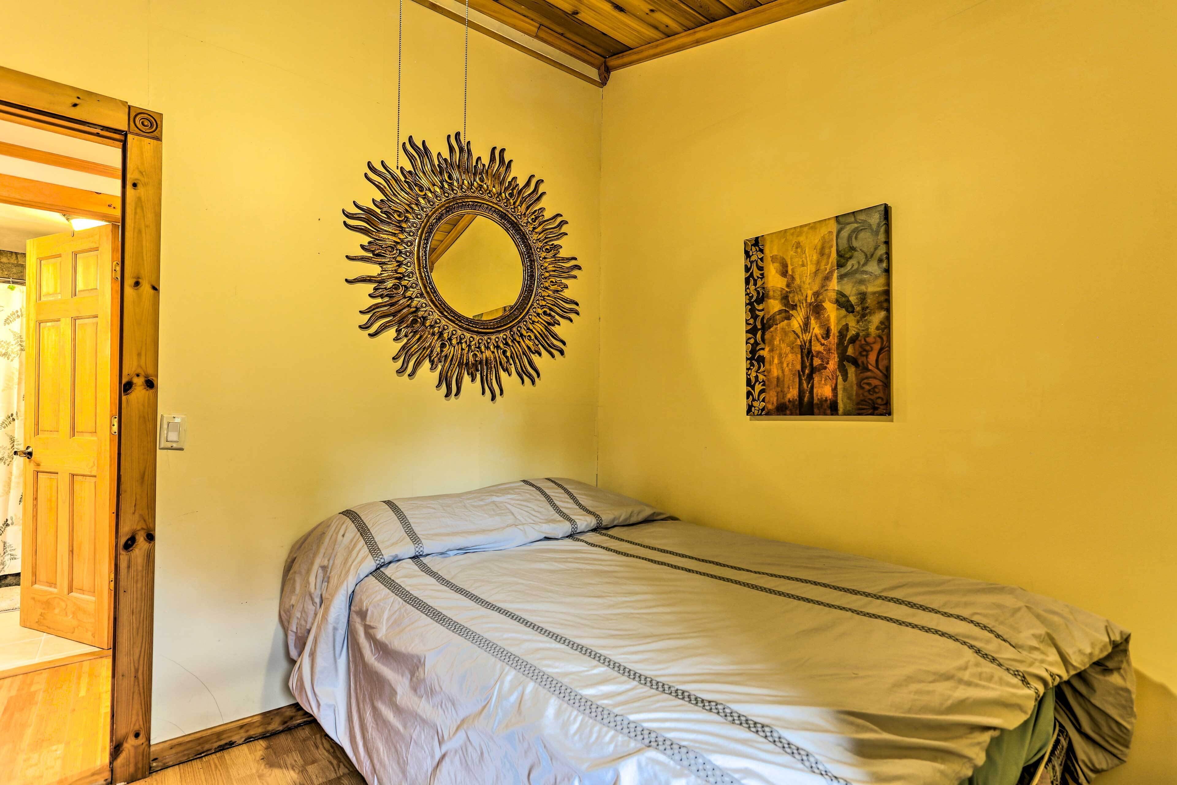 A bedroom with a bed, a mirror, and a painting on the wall.