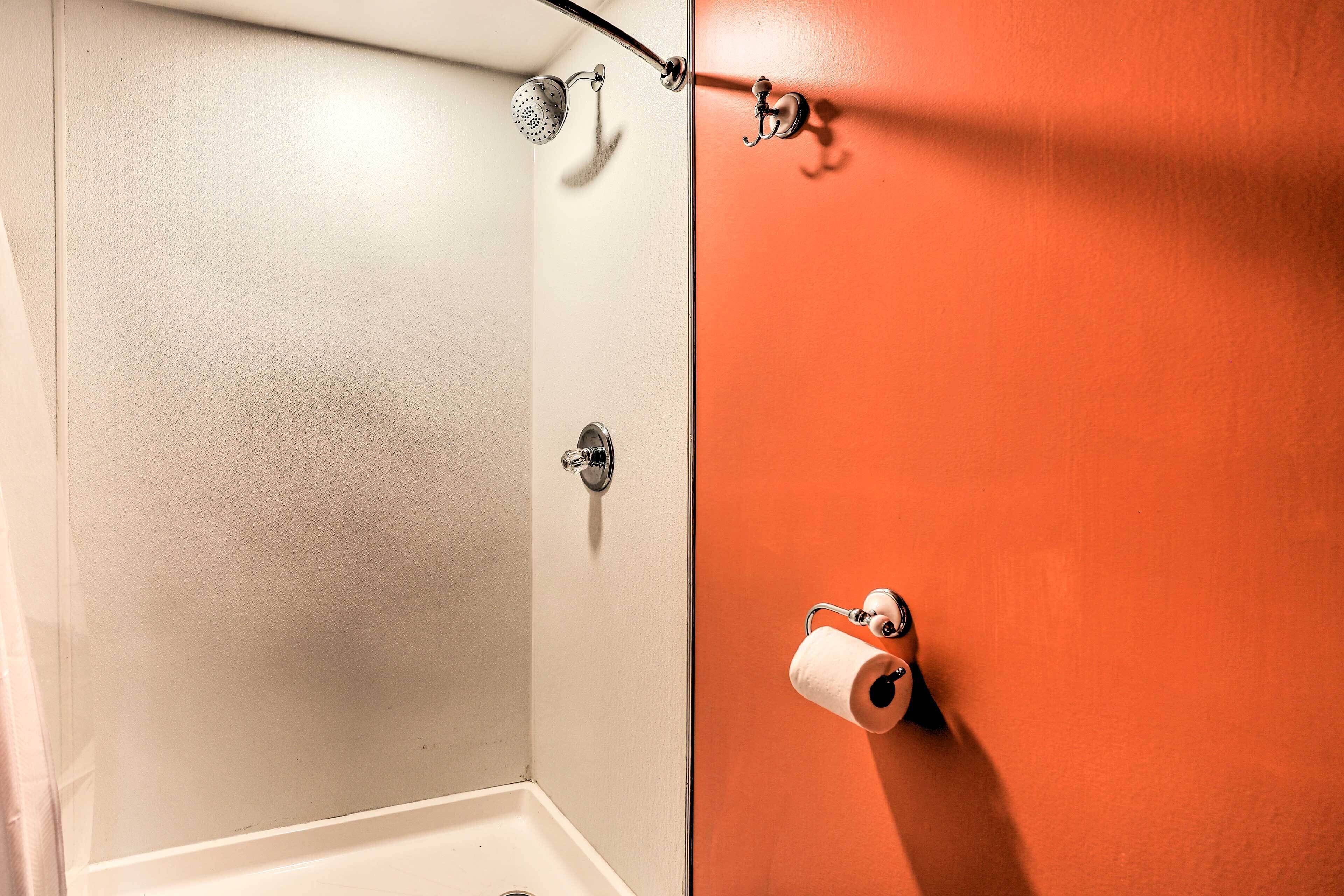 A bathroom with a shower, toilet, and a towel rack.