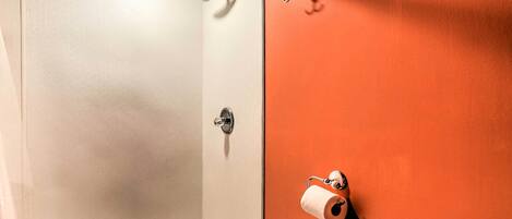 A bathroom with a shower, toilet, and a towel rack.