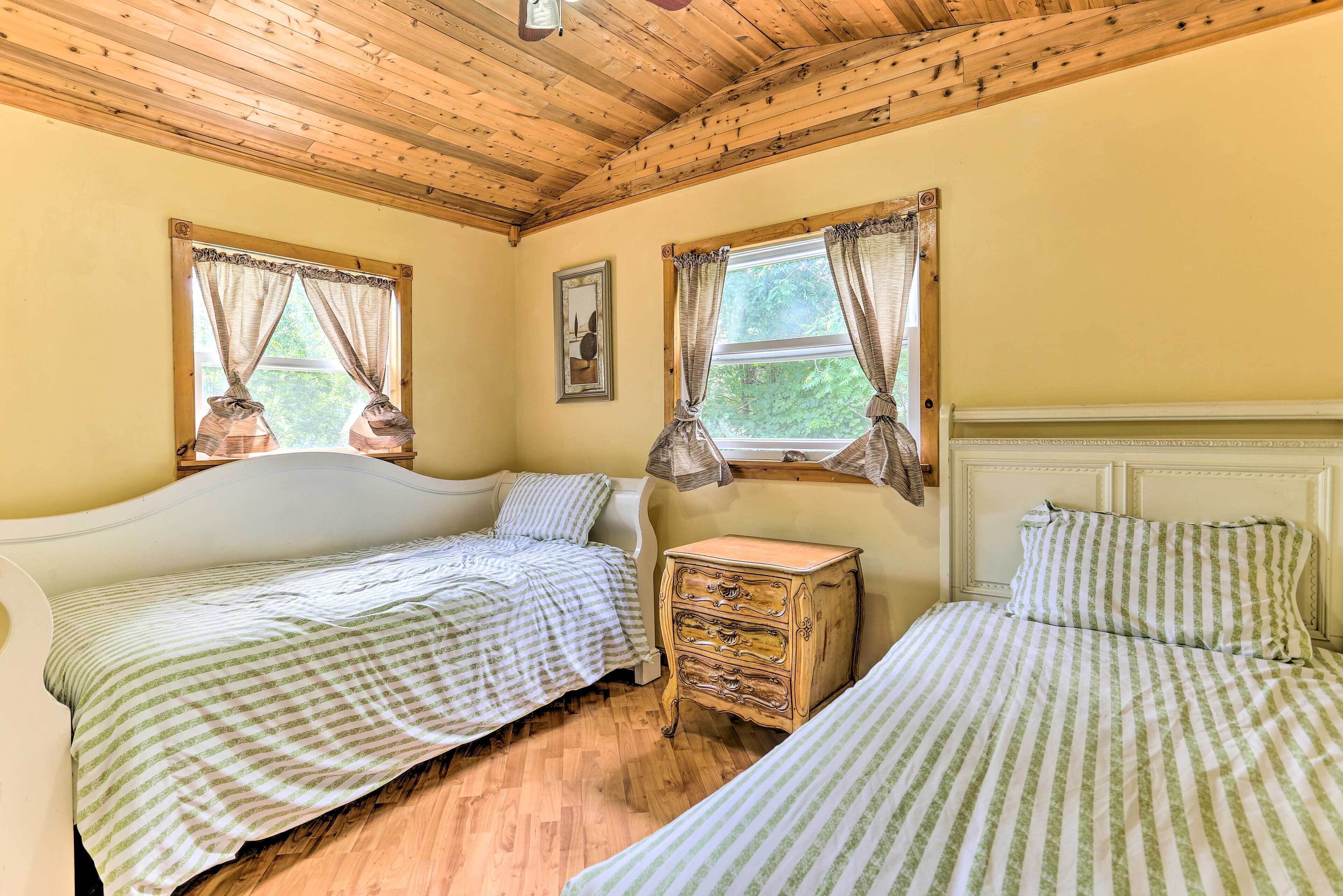 A room with two beds, wooden flooring, and a ceiling with exposed beams.